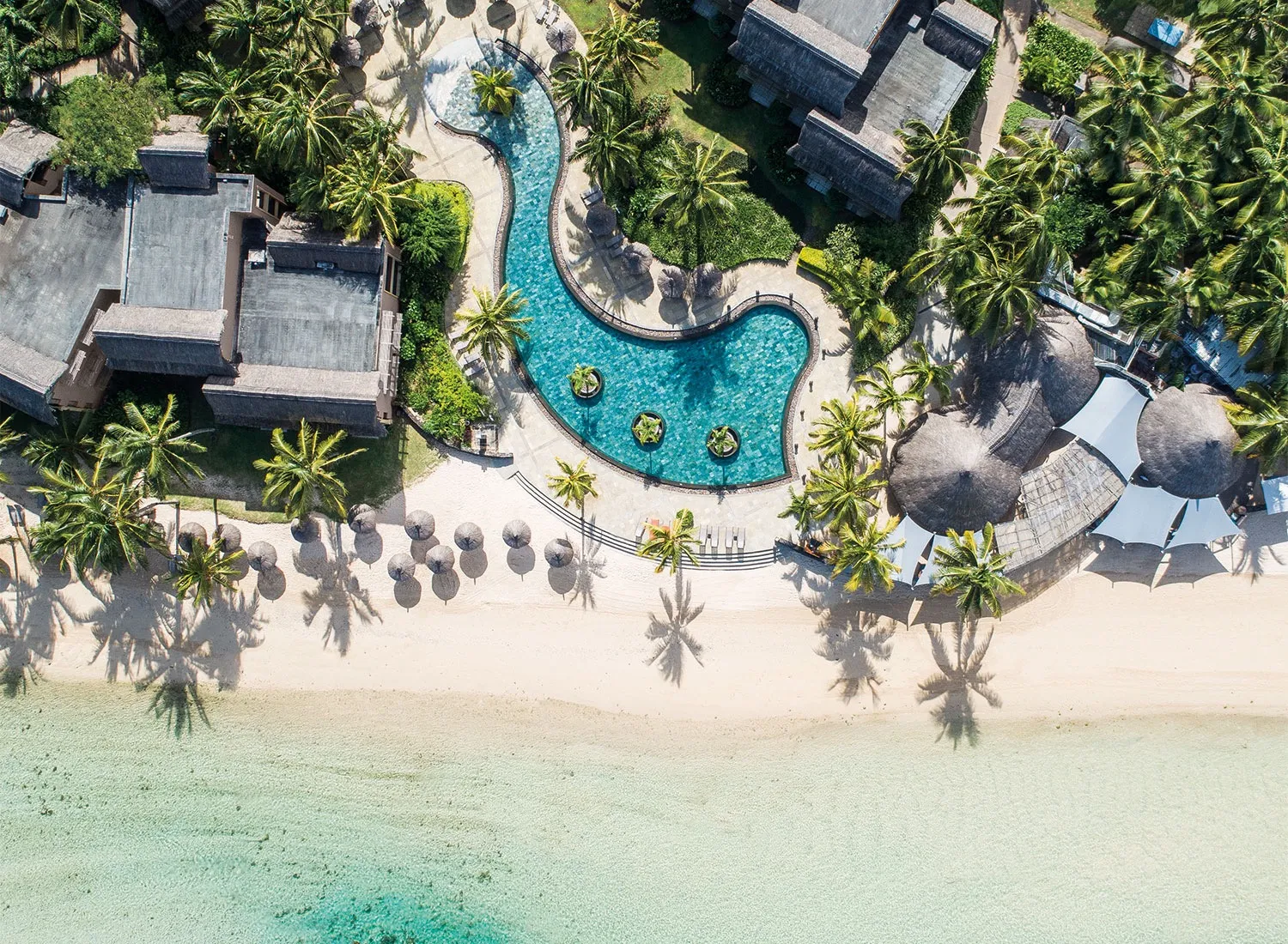 Poollandschaft und Strand des Resorts von oben