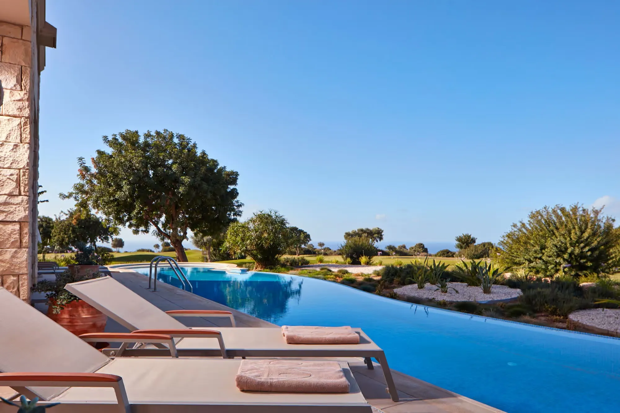 Infinity-Pool mit Sonnenliegen und Blick ins Grüne