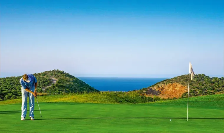 Golfer beim Putten auf dem Grün, im Hintergrund das Meer